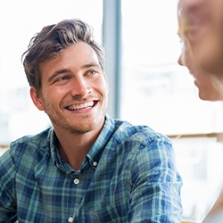 man smiling while talking to others 