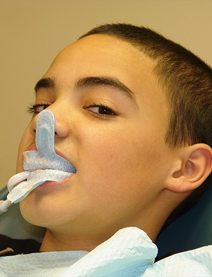 Boy getting fluoride treatment in dental chair