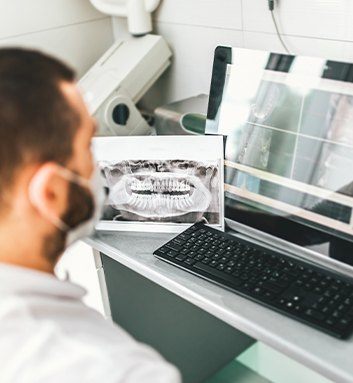 Dentist looking at X rays of teeth on computer screen