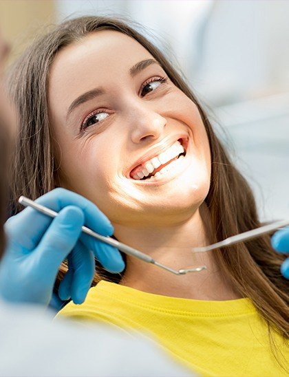 woman in yellow smiling in dental chair