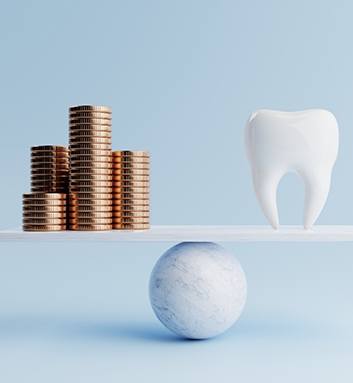 A fake tooth and golden coins on a balancing scale 