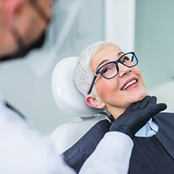 Woman with black glasses smiling at dentist