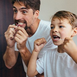 Father and son flossing their teeth together