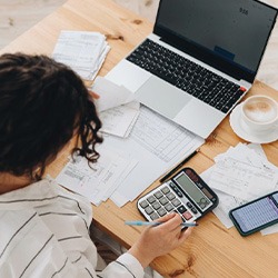 Woman sitting at her desk with a calculator and laptop