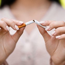 Closeup of woman breaking cigarette