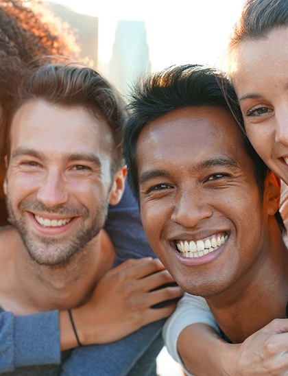 Group of adults outside smiling with arms around each other