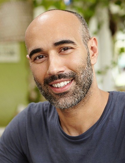 man in gray shirt smiling with dental bridges in Fort Smith