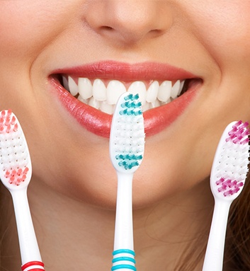 woman holding three toothbrushes