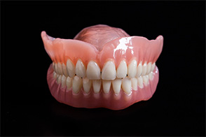 Set of full dentures against black background