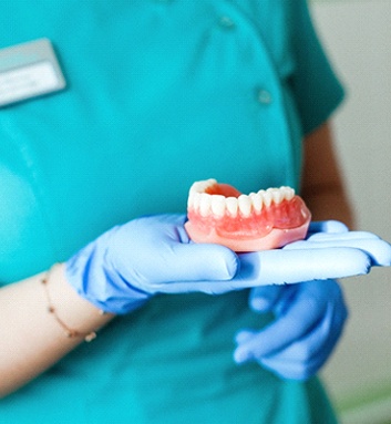 Closeup of dentist holding part of dentures in Fort Smith