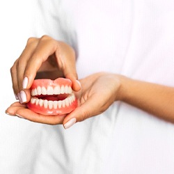 Closeup of dentist holding immediate full denture in Fort Smith