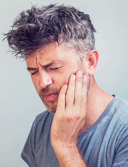 Man with a toothache in Fort Smith holding his cheek