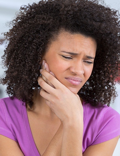 woman holding her face in pain before tooth extractions in Fort Smith