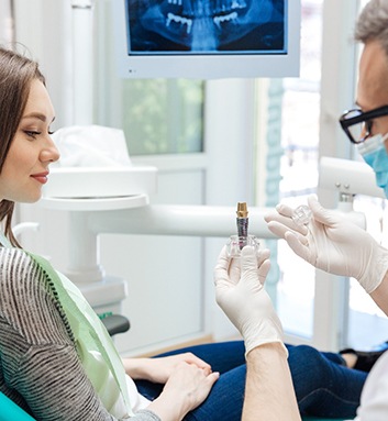 dentist showing a dental implant model to a patient