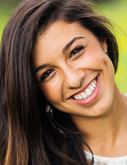 young woman smiling outside after teeth whitening in Fort Smith