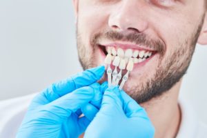 dentist holding veneers in Fort Smith up to a patient’s smile 